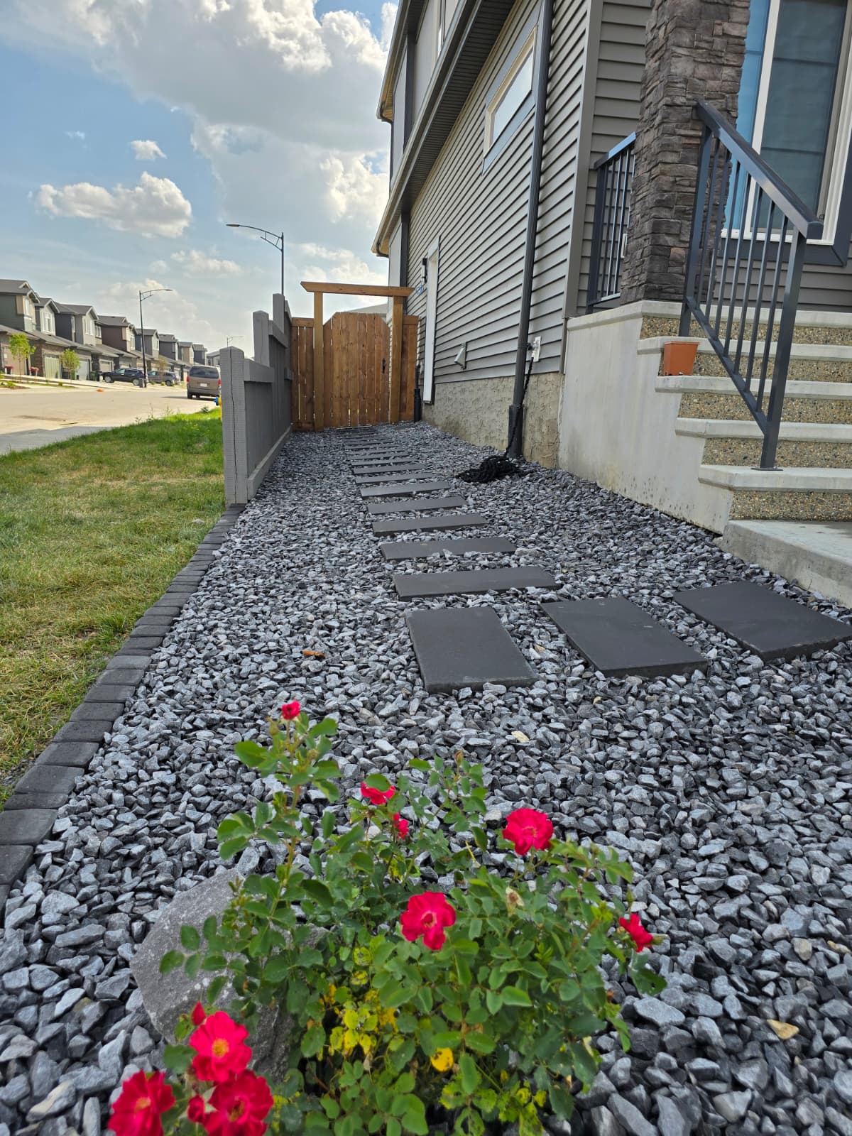 Dark slate steppers through grey gravel with pergola gate — Edmonton