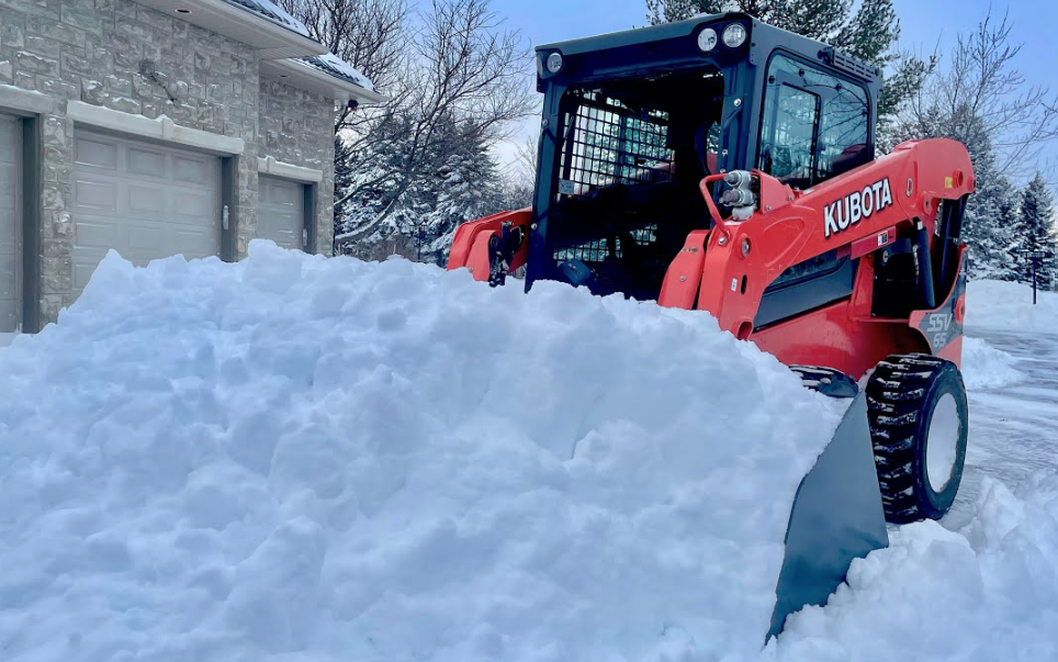 Kubota SSV skid steer clearing snow at residential driveway in Edmonton